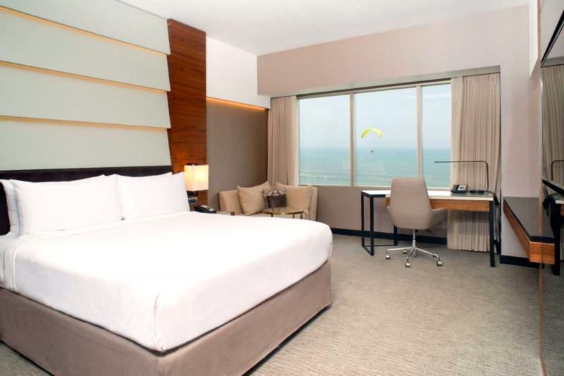 The accessible guest room, with a carpeted floor, king-sized bed, corner seating area, desk and sea view.