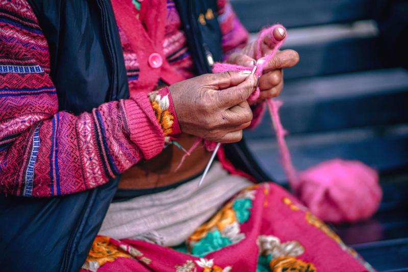 Local Quechua woman knitting colorful handcrafts.