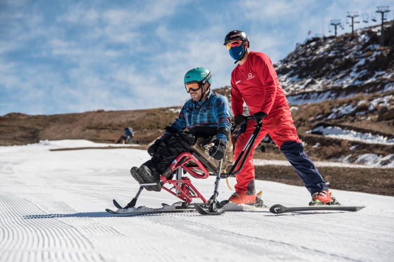 An instructor guides a student in the adaptive skiing class