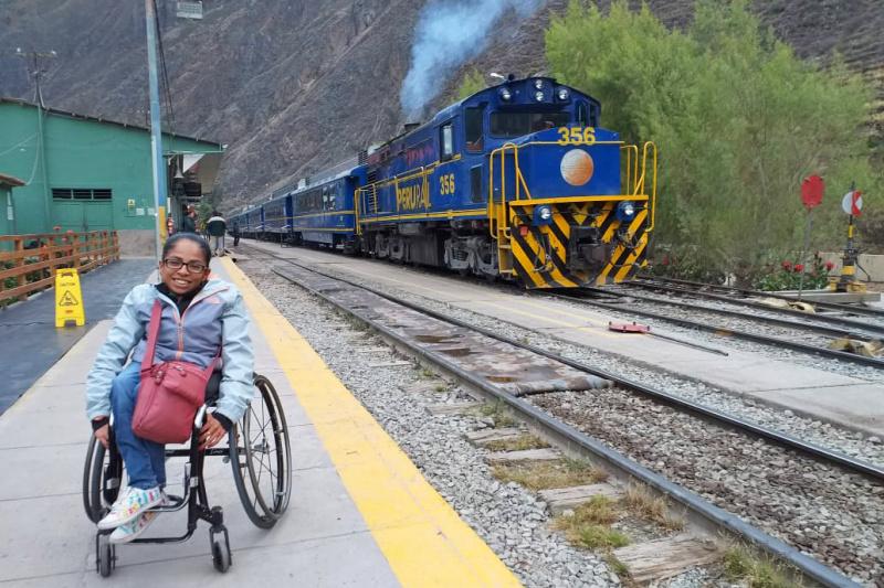 A woman in a wheelchair posing in a train station that takes you from Cusco to Aguas Calientes.